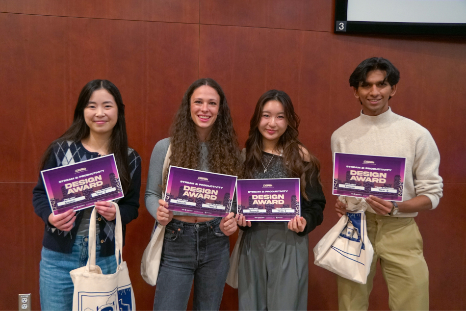 Four young adults stand side by side, smiling, each holding a purple Design Award certificate. The backdrop is a wooden-paneled wall, conveying a celebratory tone.